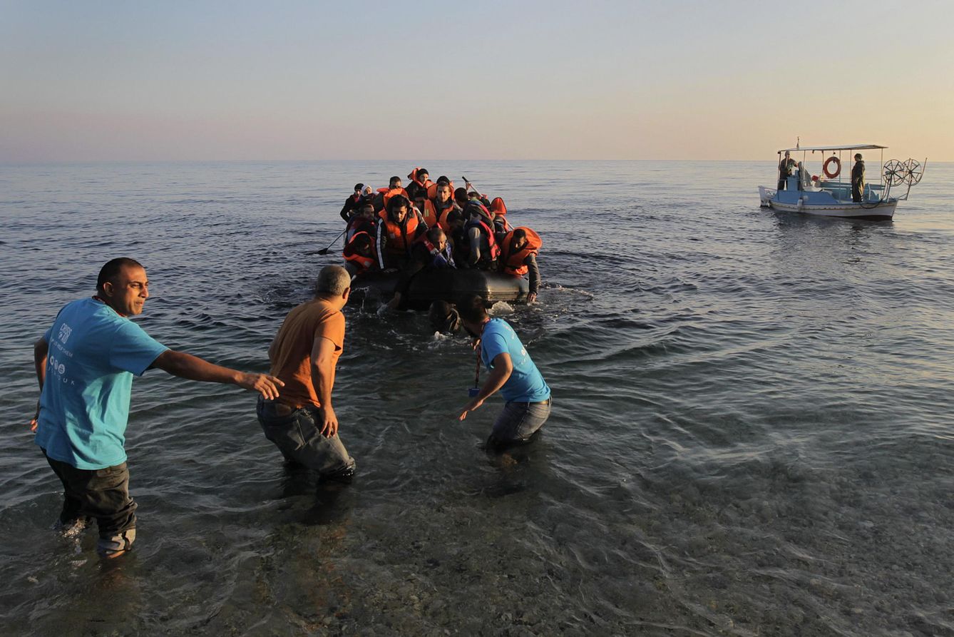Unos pescadores griegos ayudan en noviembre de 2015 a un grupo de refugiados a su llegada a la isla de Lesbos. (EFE/Orestis Panagiotou)