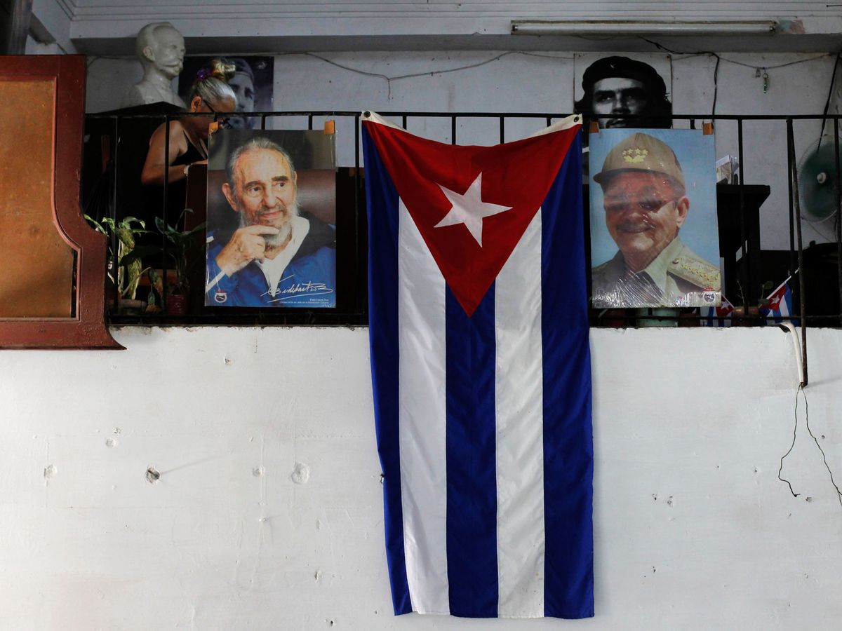Foto: Una bandera cubana, rodeada por fotografías de los dictadores Fidel y Raúl Castro. (Reuters) 