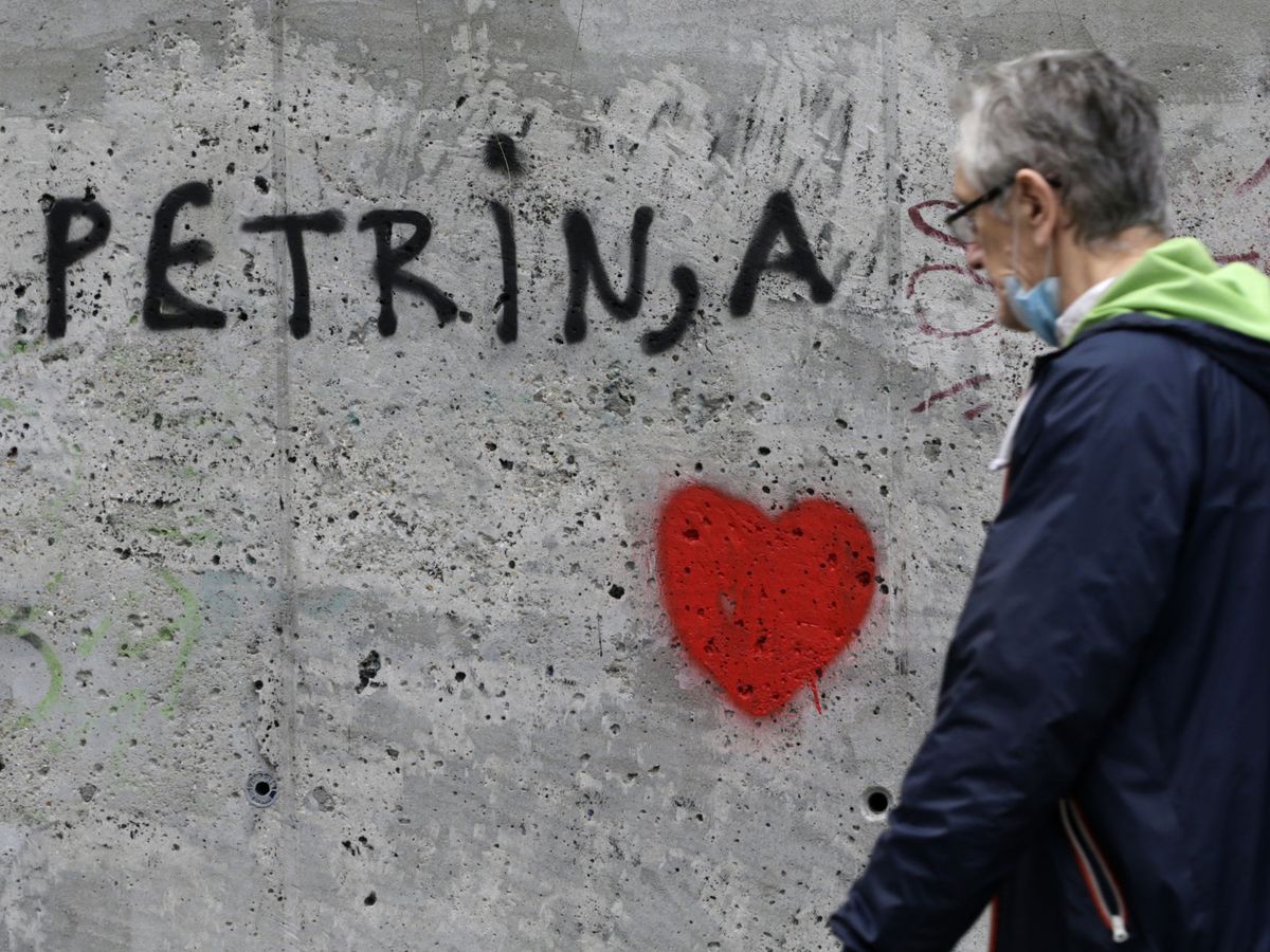 Foto: Un hombre pasa por delante de un graffiti para apoyar a la ciudad de Petrinja tras el terremoto del martes (EFE)