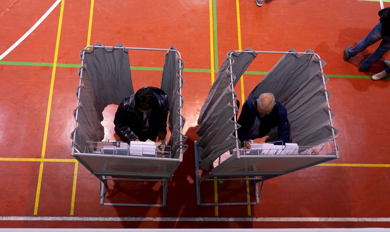 Votantes eligen sus papeletas mientras ejercen su derecho al voto este domingo en un colegio electoral de Teruel. (EFE/  Antonio García) 