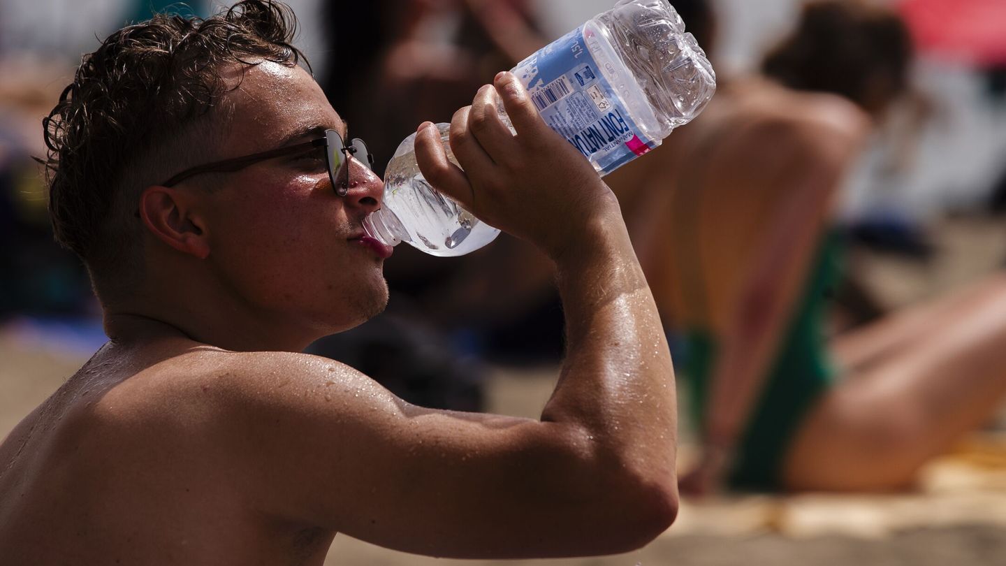 Un hombre bebe agua en la playa de la Malagueta. (EFE/Jorge Zapata).