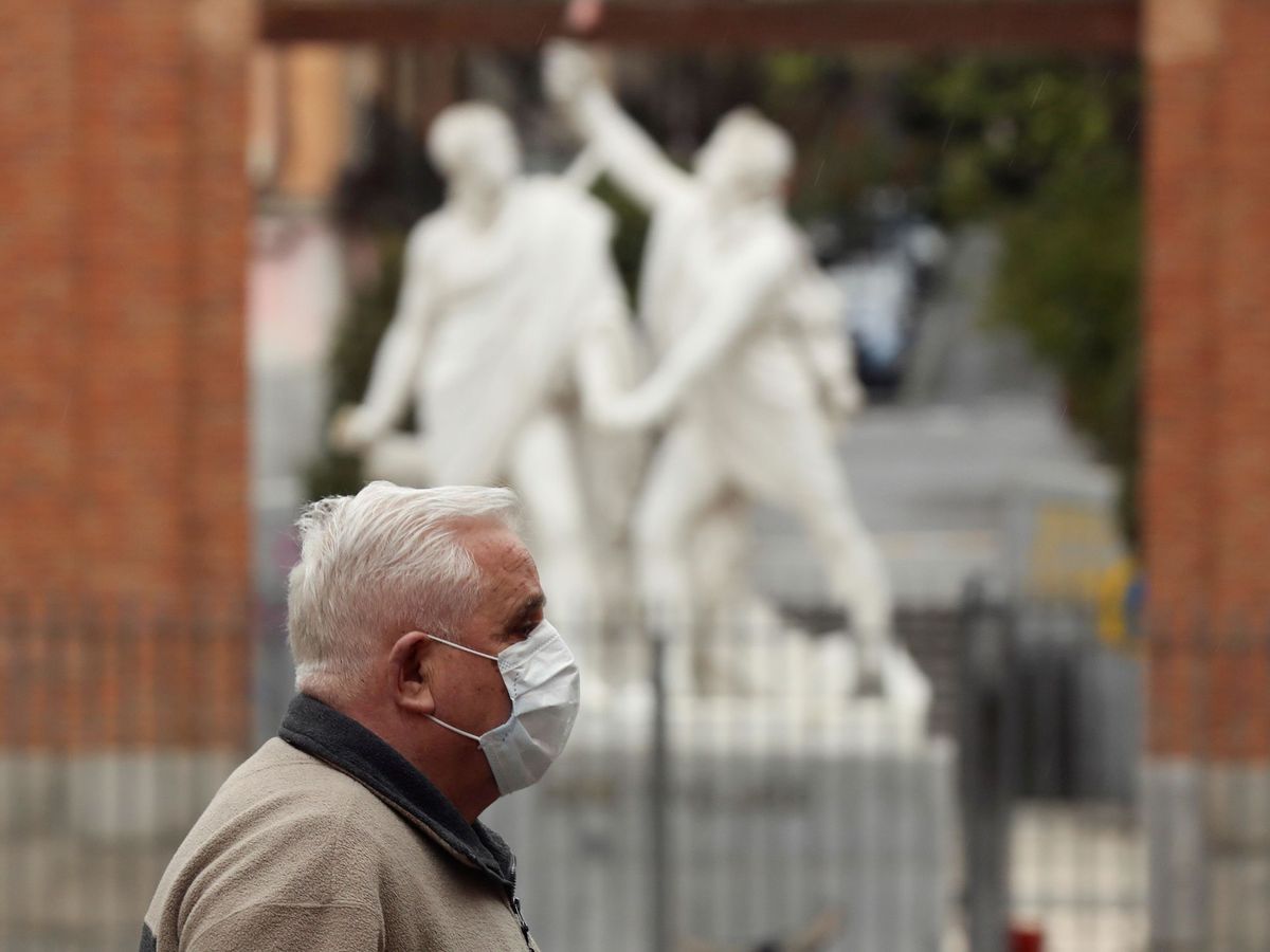 Foto: Un hombre protegido con una mascarilla transita una calle del madrileño barrio de Malasaña (EFE)