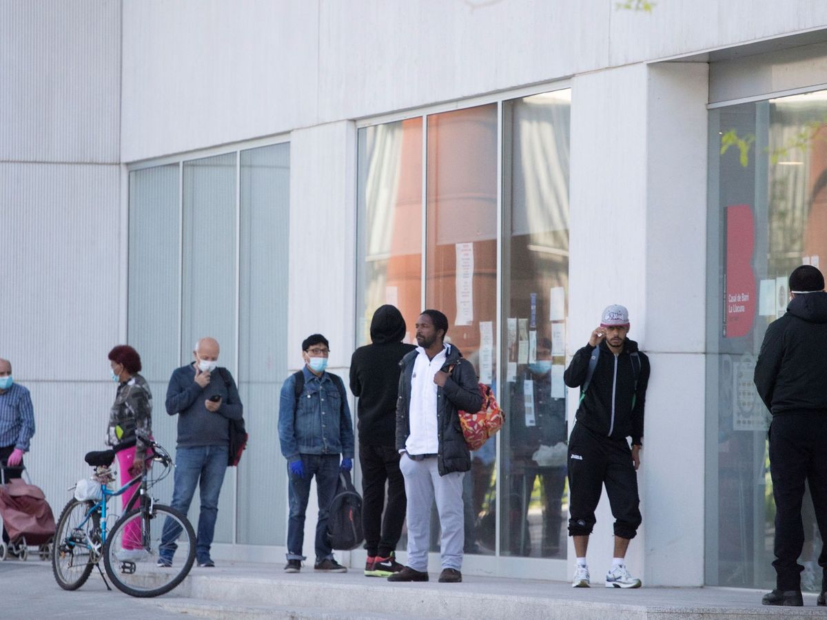 Foto: Varias personas esperan a que el centro de Casa Llacuna en Poblenou, Barcelona, reparta raciones de comida (EFE)