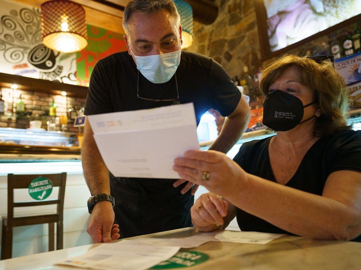 Foto: Personal de una cafetería de Santa Cruz de Tenerife, comprueba el certificado covid de una clienta. (EFE)