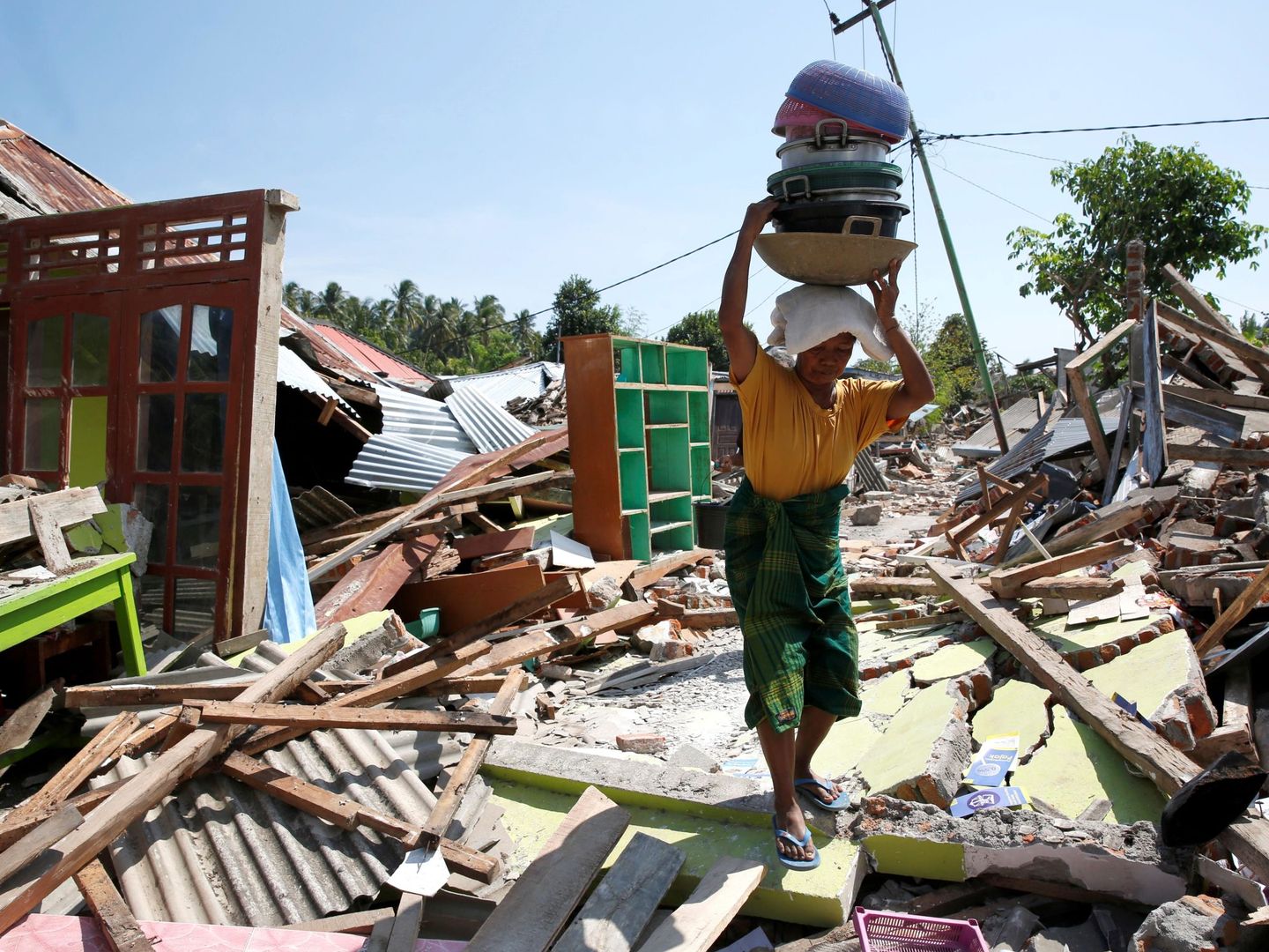 Una mujer carga con sus pertenencias entre los escombros el 10 de agosto de 2018, tras el terremoto que el pasado domingo azotó el norte de la isla de Lombok (EFE)