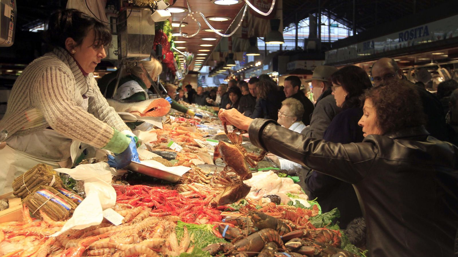 Foto: Últimas compras en una pescadería del Mercado de la Boquería de Barcelona para la cena de Nochebuena y la comida de Navidad. (Efe) 