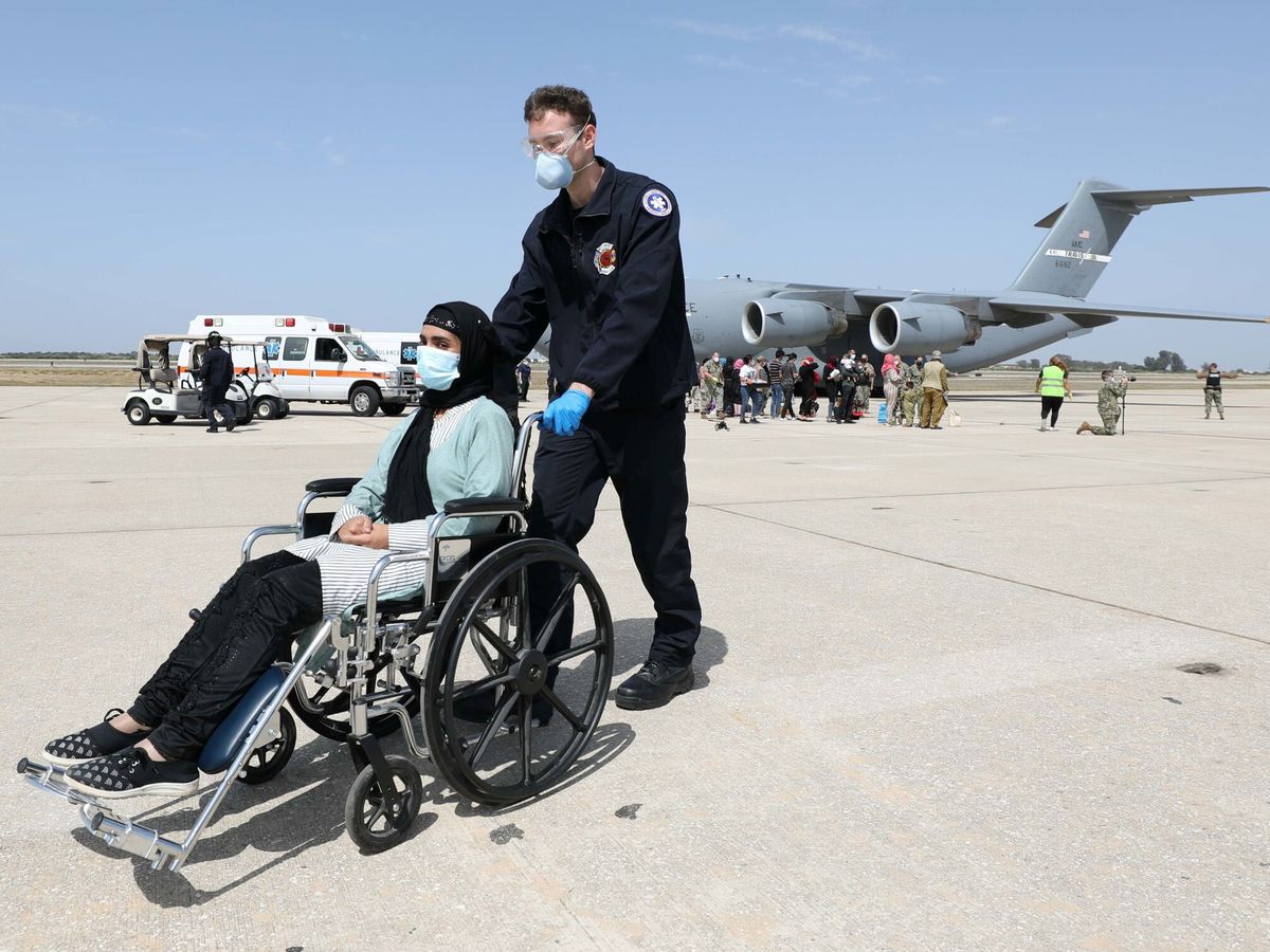 Foto: Una ciudadana afgana es ayudada por personal de la base naval de Rota tras su llegada en un vuelo estadounidense. (Reuters)