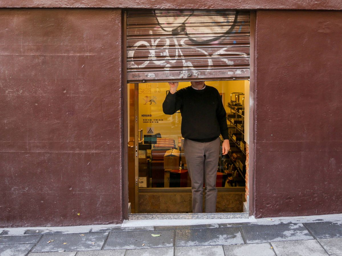 Foto: Un hombre baja el cierre de una tienda. (Europa Press)
