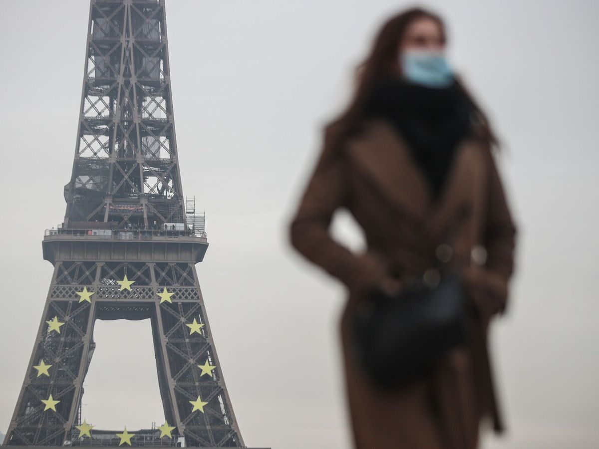 Foto: Una mujer con mascarilla pasea junto a la Torre Eiffel de Paris. (EFE/EPA/Mohammed Badra)