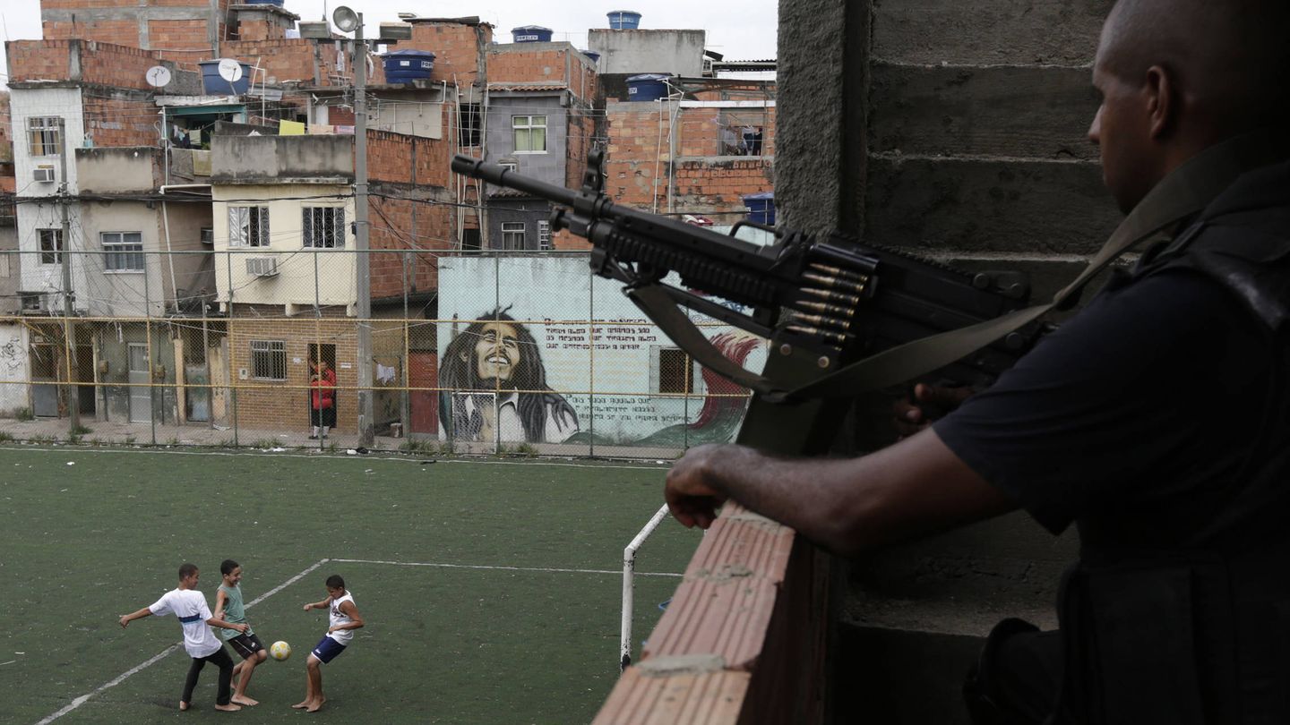 Niños juegan al fútbol mientras un policía vigila en la favela de La Maré, en Río de Janeiro. (Reuters)