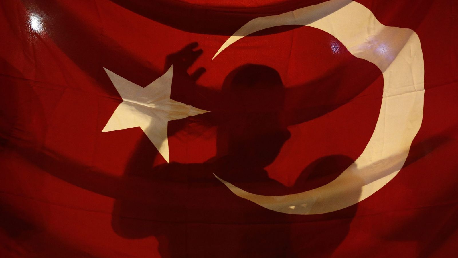 Foto: Un simpatizante de Erdogan grita consignas tras la bandera. (Reuters)