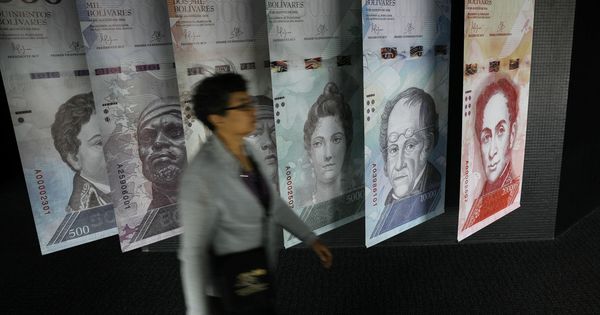 Foto: Una mujer pasa por delante de carteles de billetes de bolívares en el Banco Central de Venezuela, en Caracas, el 23 de mayo de 2017. (Reuters)