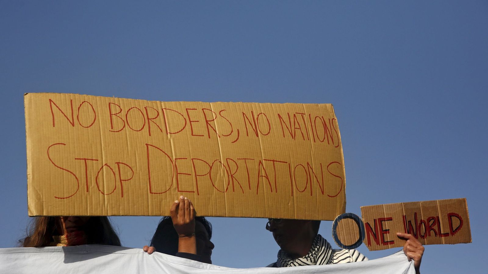 Foto: Activistas sostienen carteles improvisados con cartones en los que piden frenar las deportaciones. (Efe)