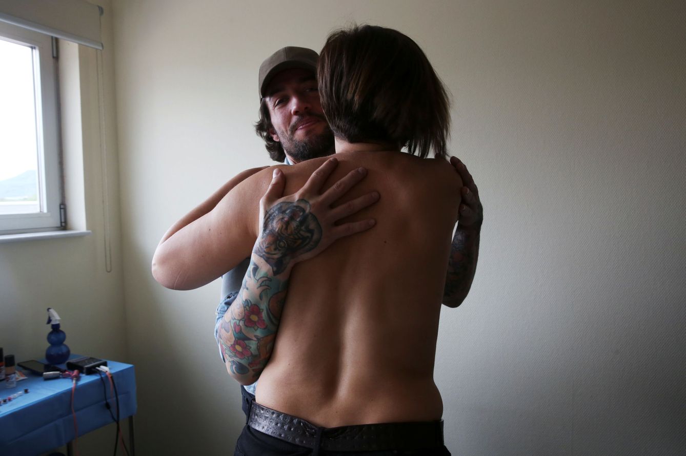 Un tatuador que trabaja con personas que han pasado por un cáncer abraza a Mamen Malagon tras tatuarle un pezón en su pecho reconstruido después de una mastectomía. (Reuters)