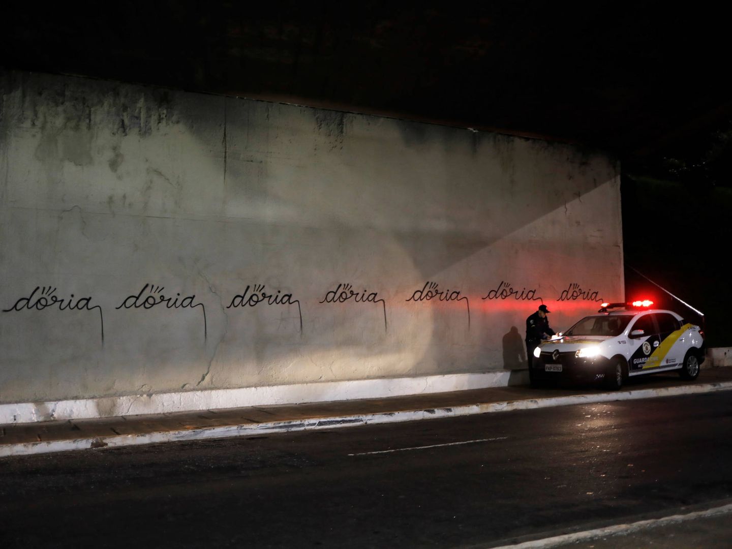 Un coche de policía investiga unas pintadas con el nombre de Doria realizadas por un artista llamado Iaco, en la avenida 23 de Maio de Sao Paulo, en marzo de 2017. (Reuters)