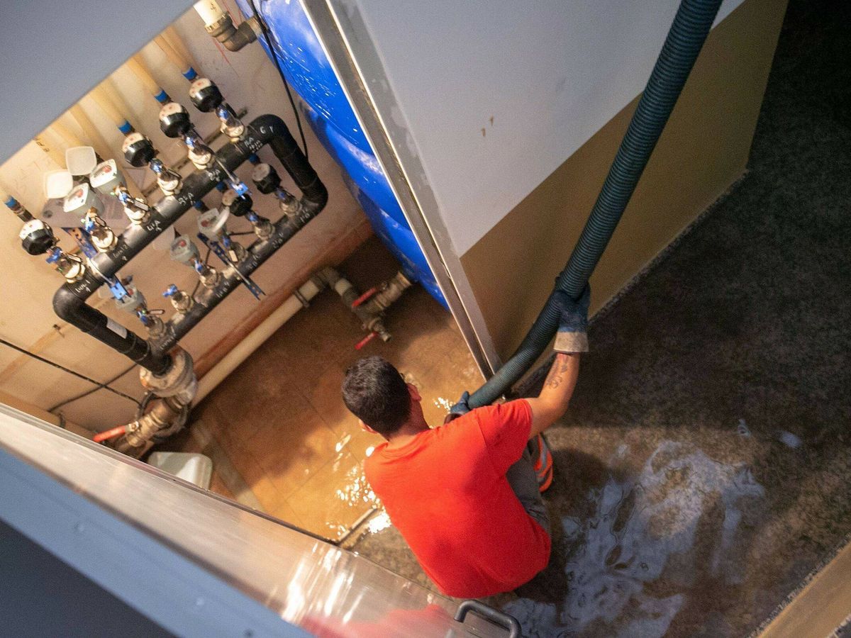 Foto: Uno operario achica agua con una bomba del cuarto de contadores. (EFE/Javier Cebollada)