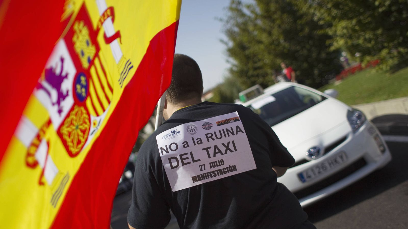 Foto: Un taxista sostiene una bandera de España durante una manifestación del sector en Madrid. (Foto: Reuters)