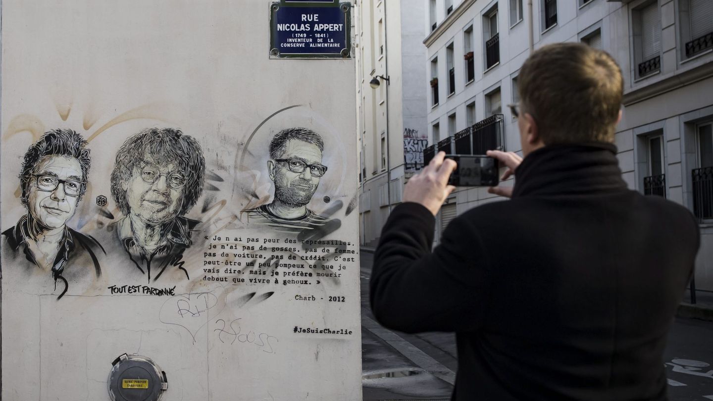 Un hombre fotografía una pintada en la que aparecen los dibujantes asesinados en la sede de 'Charlie Hebdo'. (EFE)