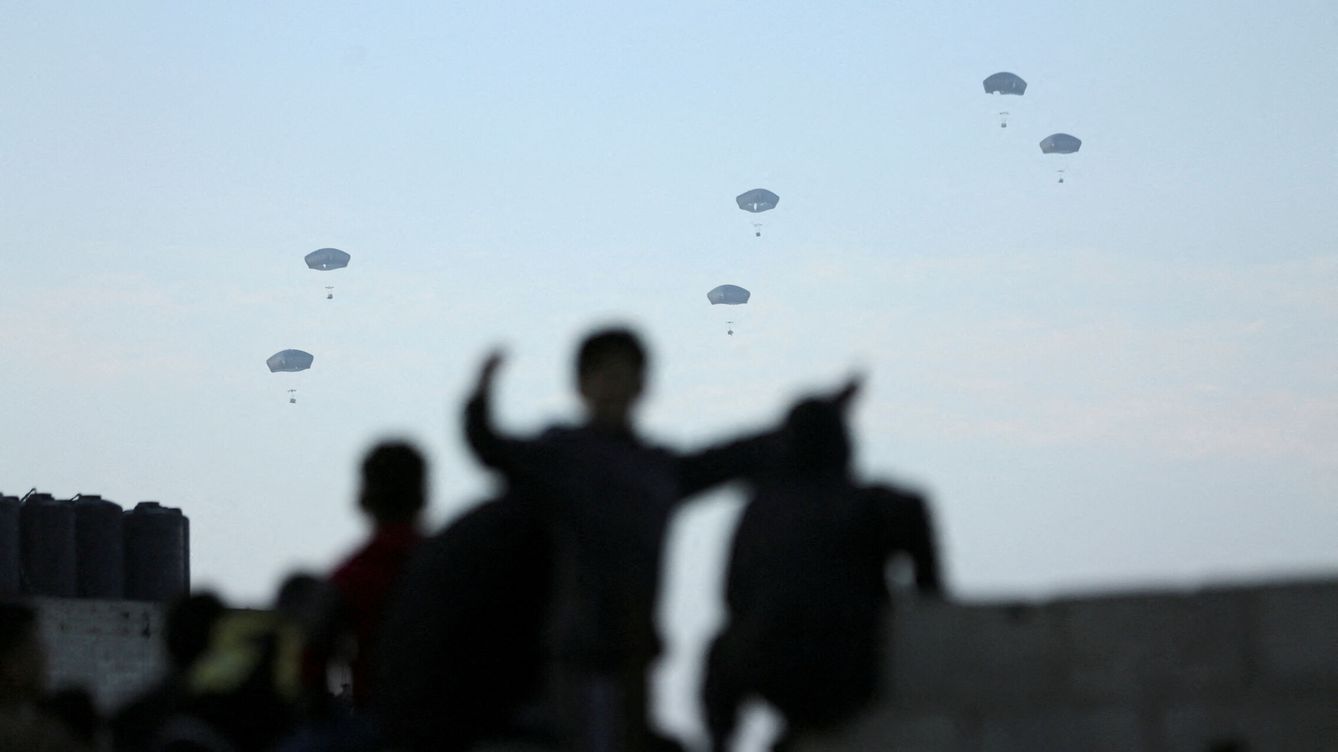 Foto: Varias personas observan cómo el ejército estadounidense lleva a cabo su primer lanzamiento de ayuda sobre Gaza. (Reuters/Kosay Al Nemer)