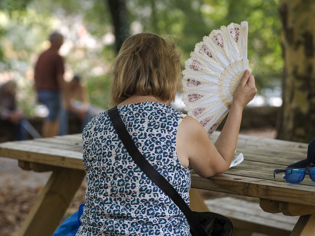 Foto: Una mujer se abanica en el parque del río Miño durante la ola de calor. (EFE/Eliseo Trigo)