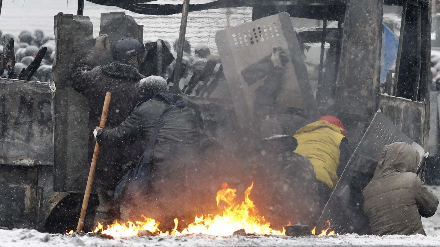 Manifestantes se protegen durante choques con la Policía (Reuters).