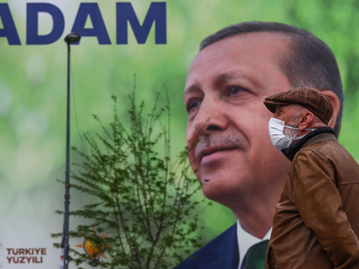 Foto: Un hombre con la cara tapada frente a un enorme cartel con la imagen del presidente turco Recep Tayyip Erdogan. (EFE/Sedat Suna)