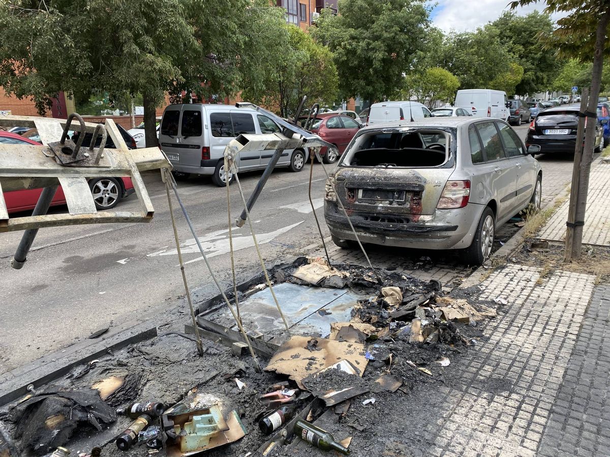 Foto: Un contenedor calcinado, junto a un coche quemado este lunes, en la calle Beasaín, en Orcasitas. (C. B.)