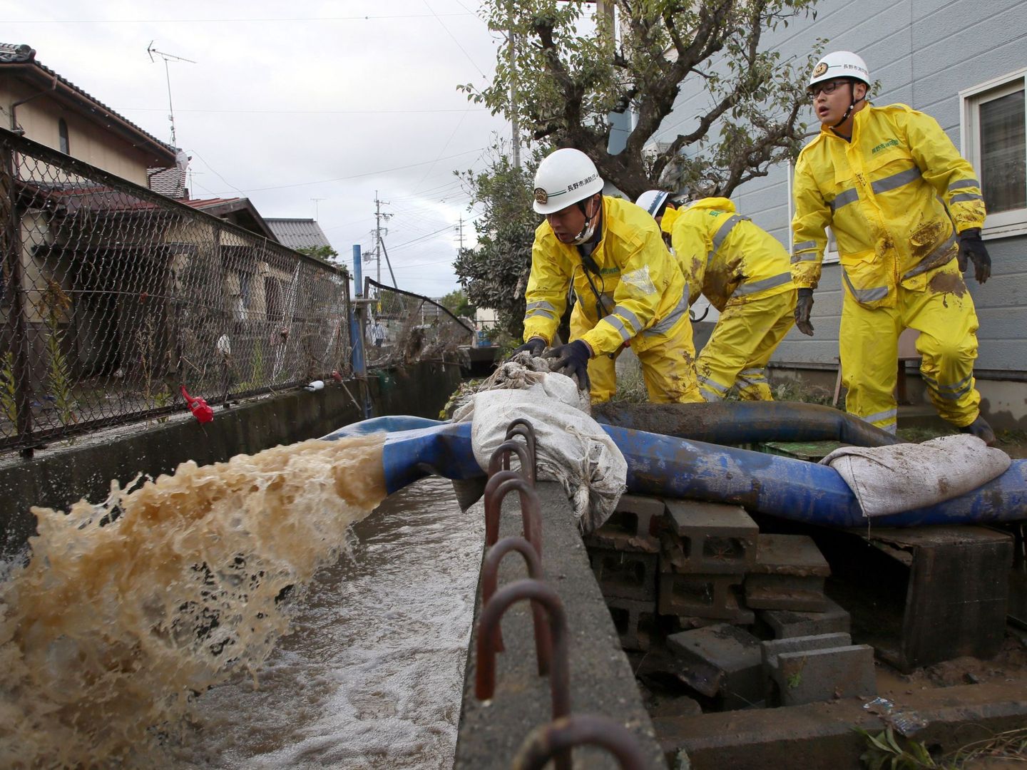 Varios operarios del servicio de emergencia ayudan a achicar agua. (EFE)
