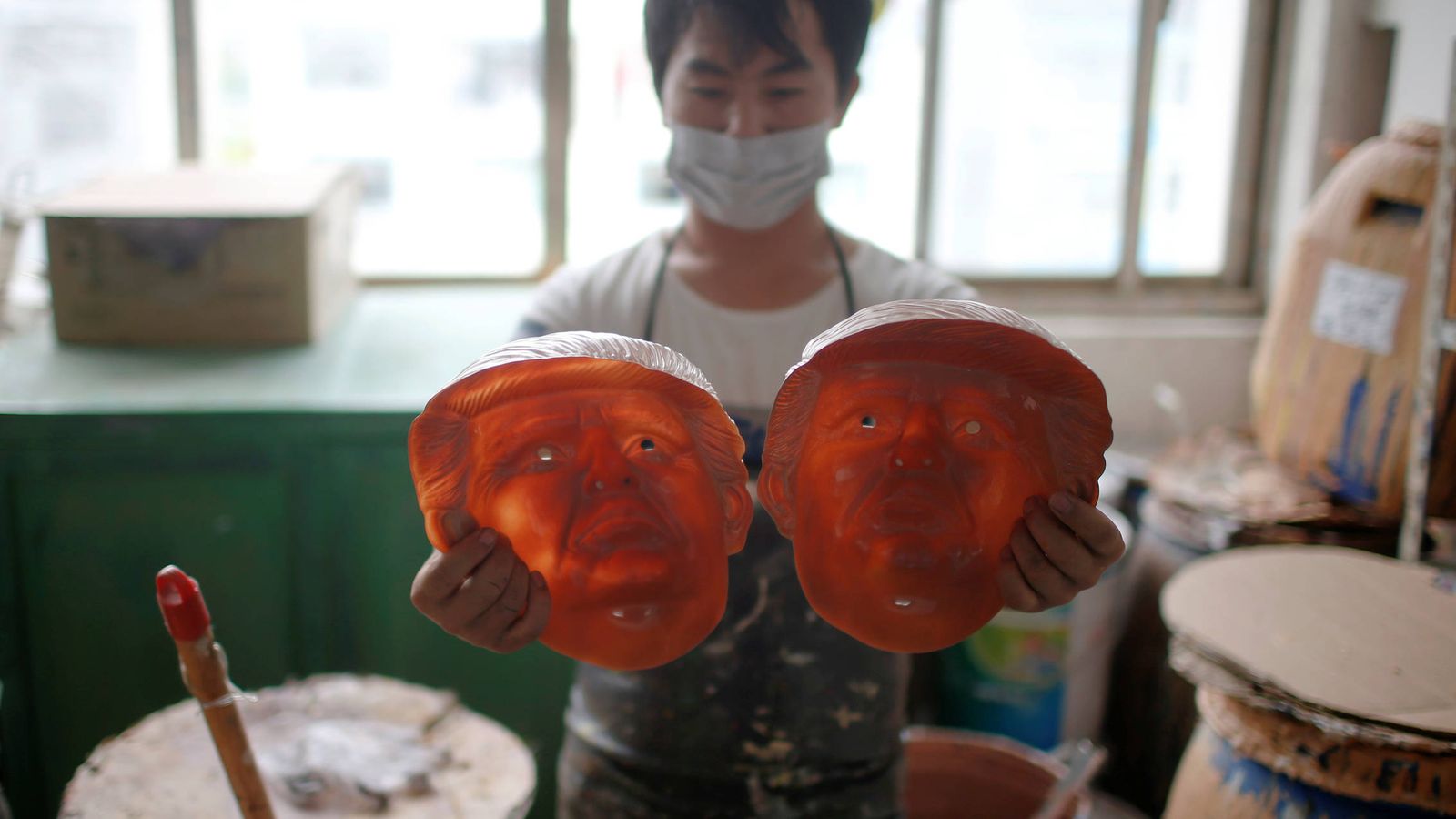 Foto: Un trabajador observa dos caretas de Donald Trump en una fábrica de Jinhua, en la provincia de Zhejiang (Reuters).