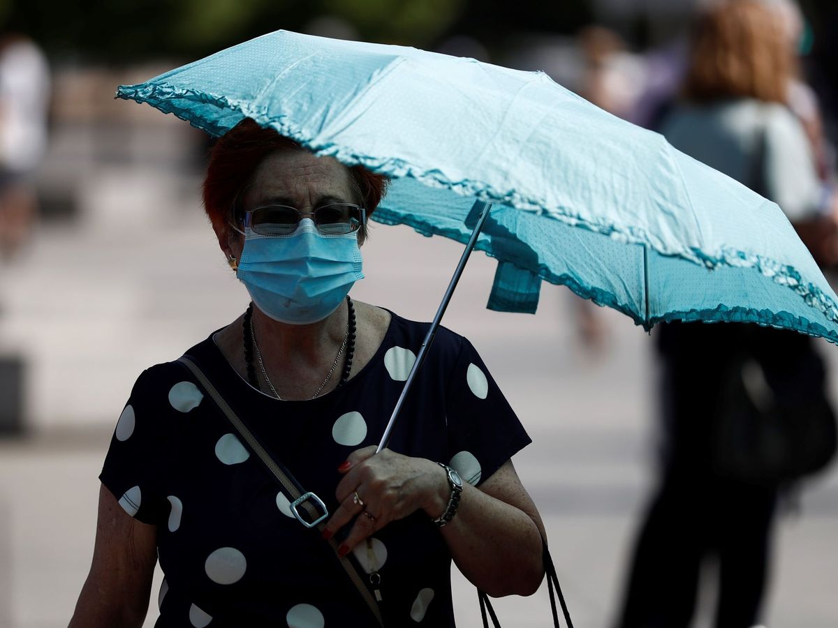 Foto: Una mujer pasea por Madrid protegida con una sombrilla (EFE)