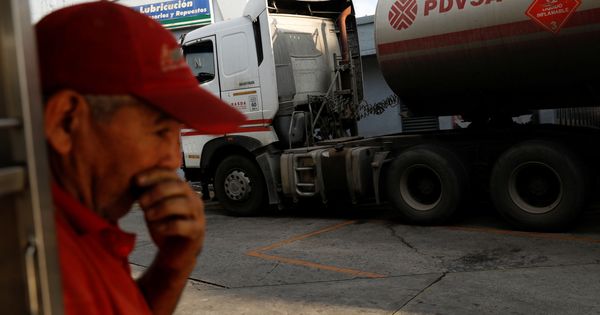 Foto: Un empleado de una gasolinera estatal, frente a un camión cisterna de PDVSA. (Reuters)