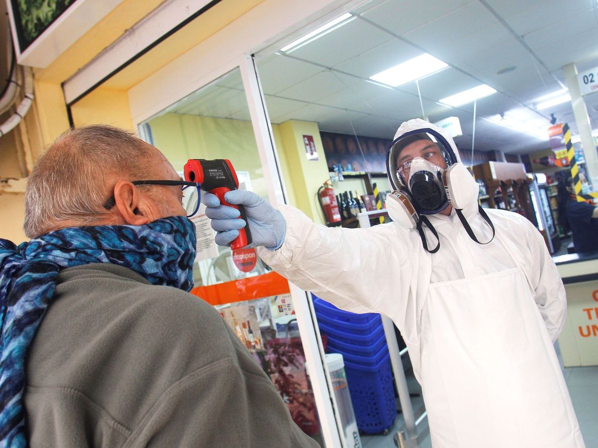 Foto: Un empleado del supermercado toma la temperatura a los clientes. (EFE)