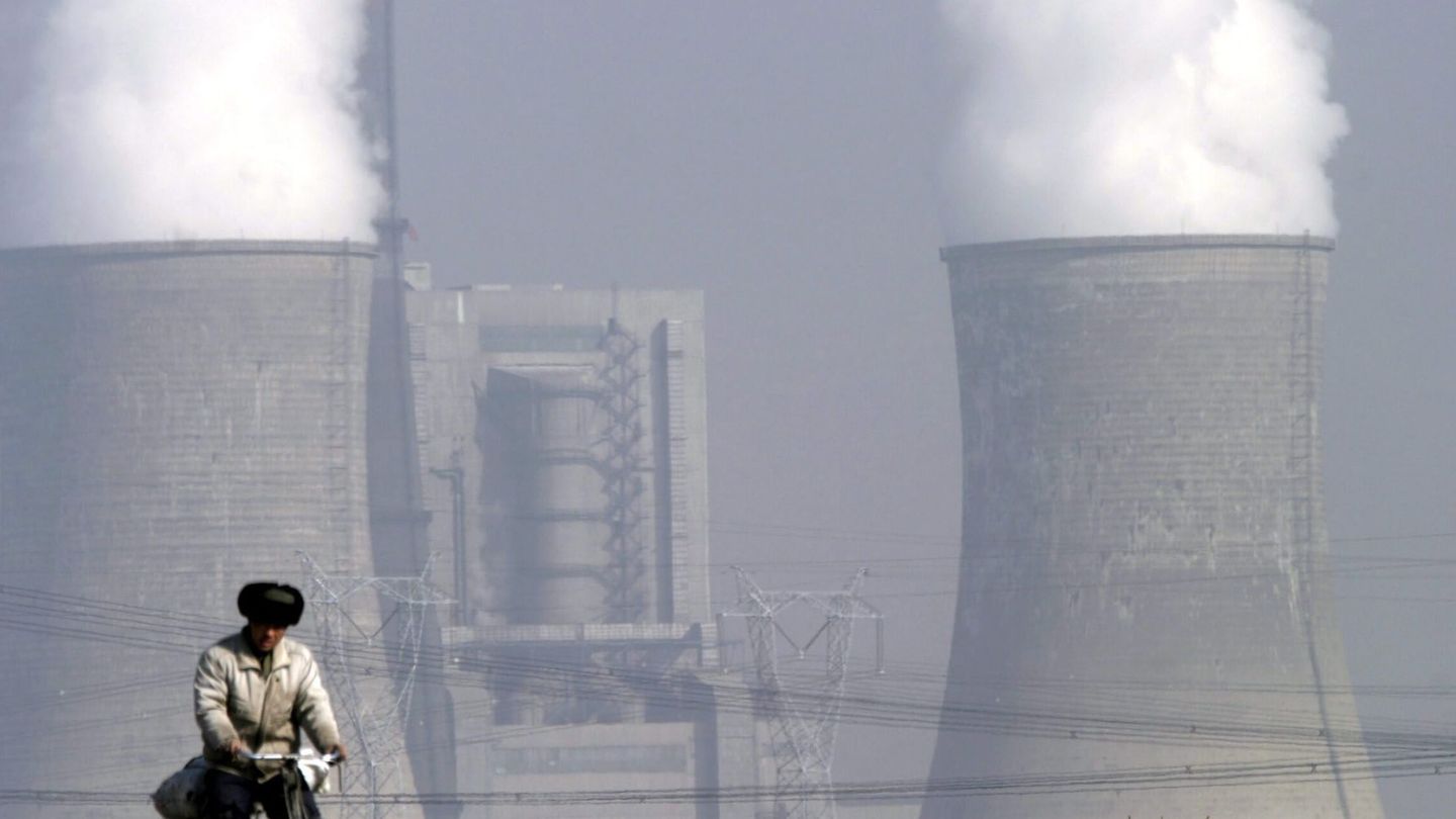 Un ciclista circula junto a una central de carbón en China (EFE/ Qilai Shen)