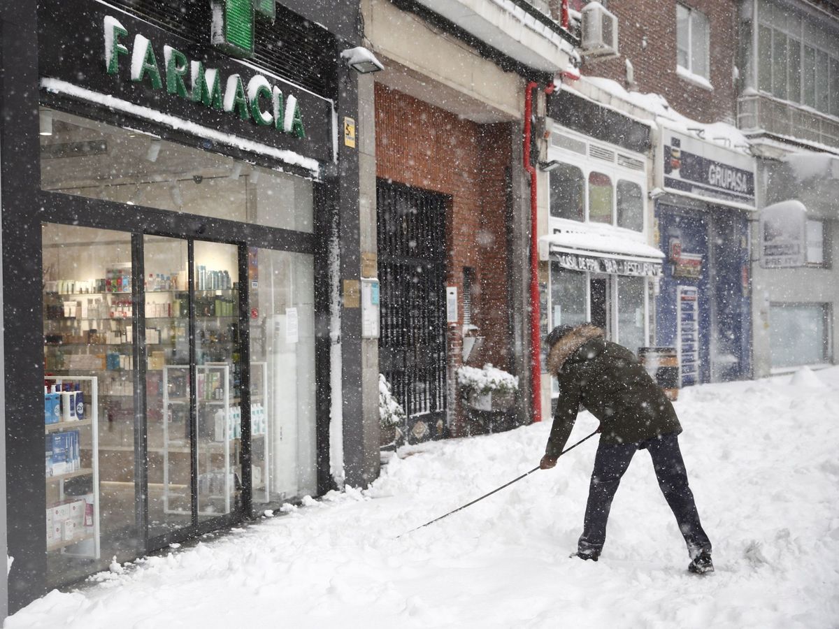 Foto: Una persona retira nieve a la entrada de un comercio. (EFE)