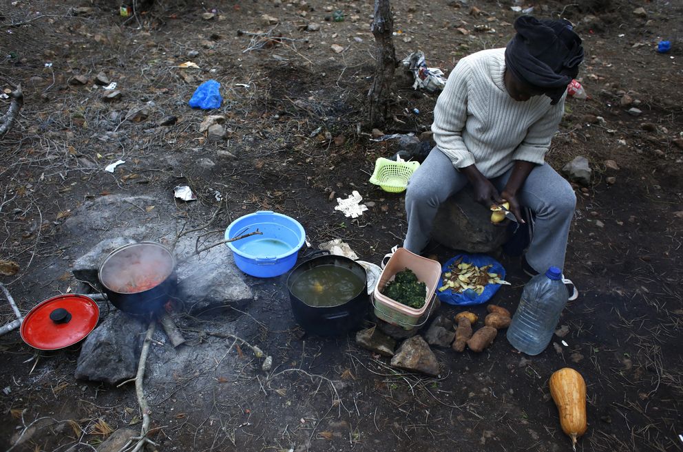Rachel, una inmigrante de Camerún, cocina en el campamento clandestino de Bolingo, cerca de Melilla (Reuters).