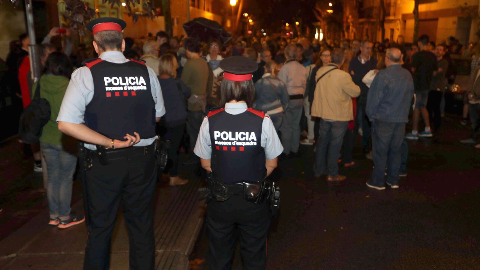 Foto: Dos Mossos custodian la puerta de un colegio en el barrio de Sants de Barcelona, en el que una multitud esperaba para votar. (EFE)