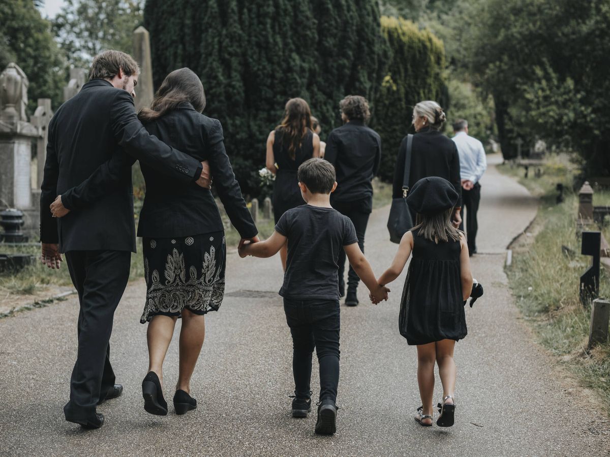 Foto: Una familia vestida de negro en un cementerio (iStock)