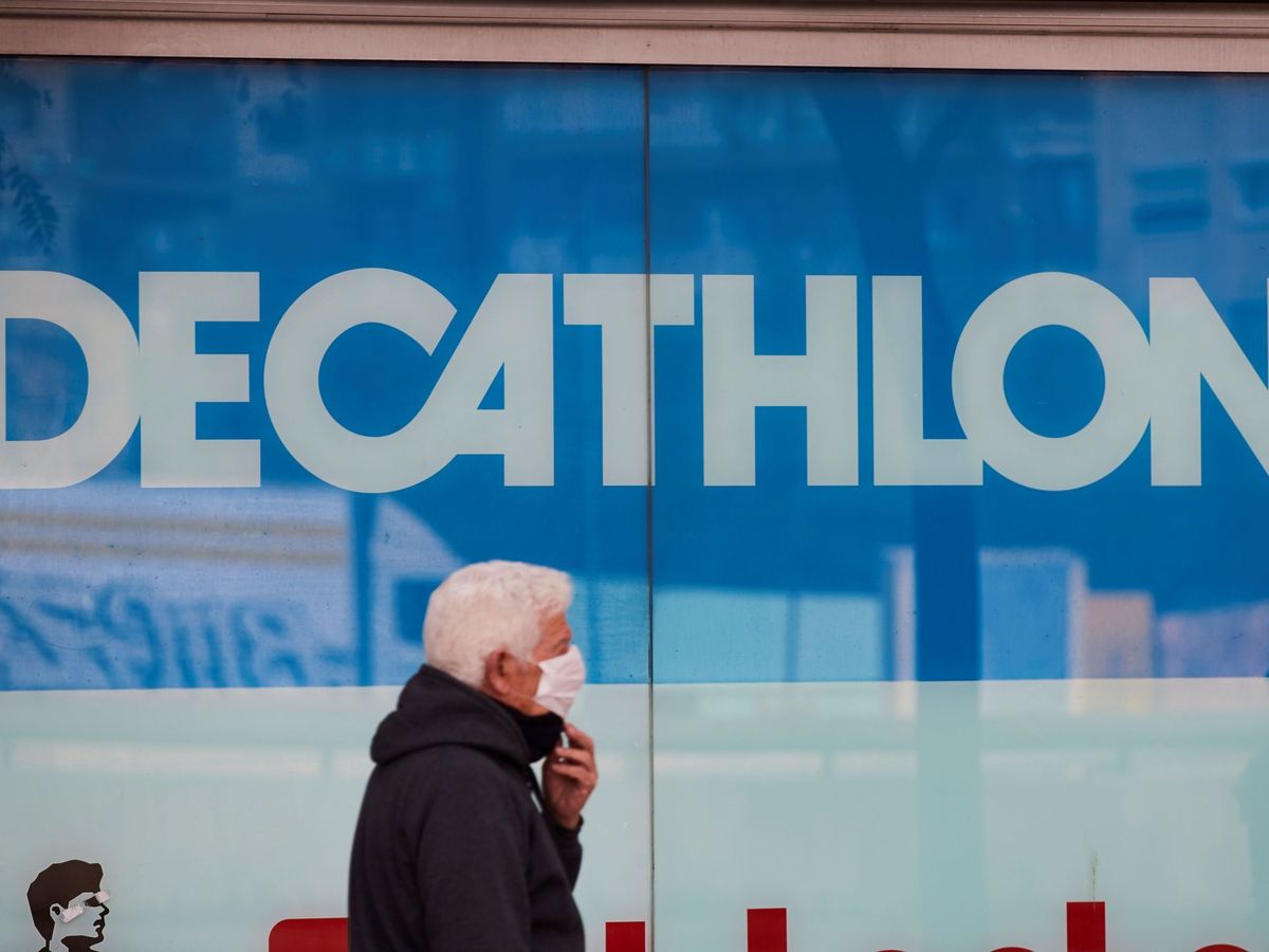 Foto: Un hombre con mascarilla pasa junto a una tienda de Decathlon en Barcelona (EFE)