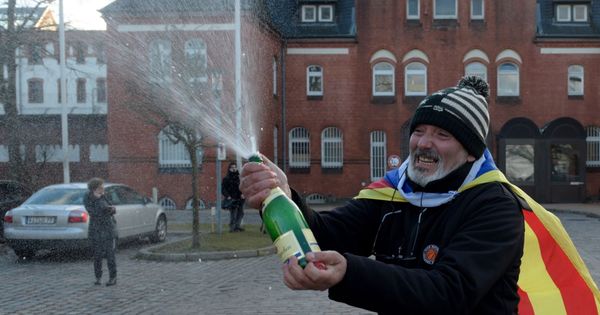 Foto: Un hombre con una bandera estelada celebra con champán frente la cárcel de Neumünster la decisión de la Justicia alemana. (EFE)