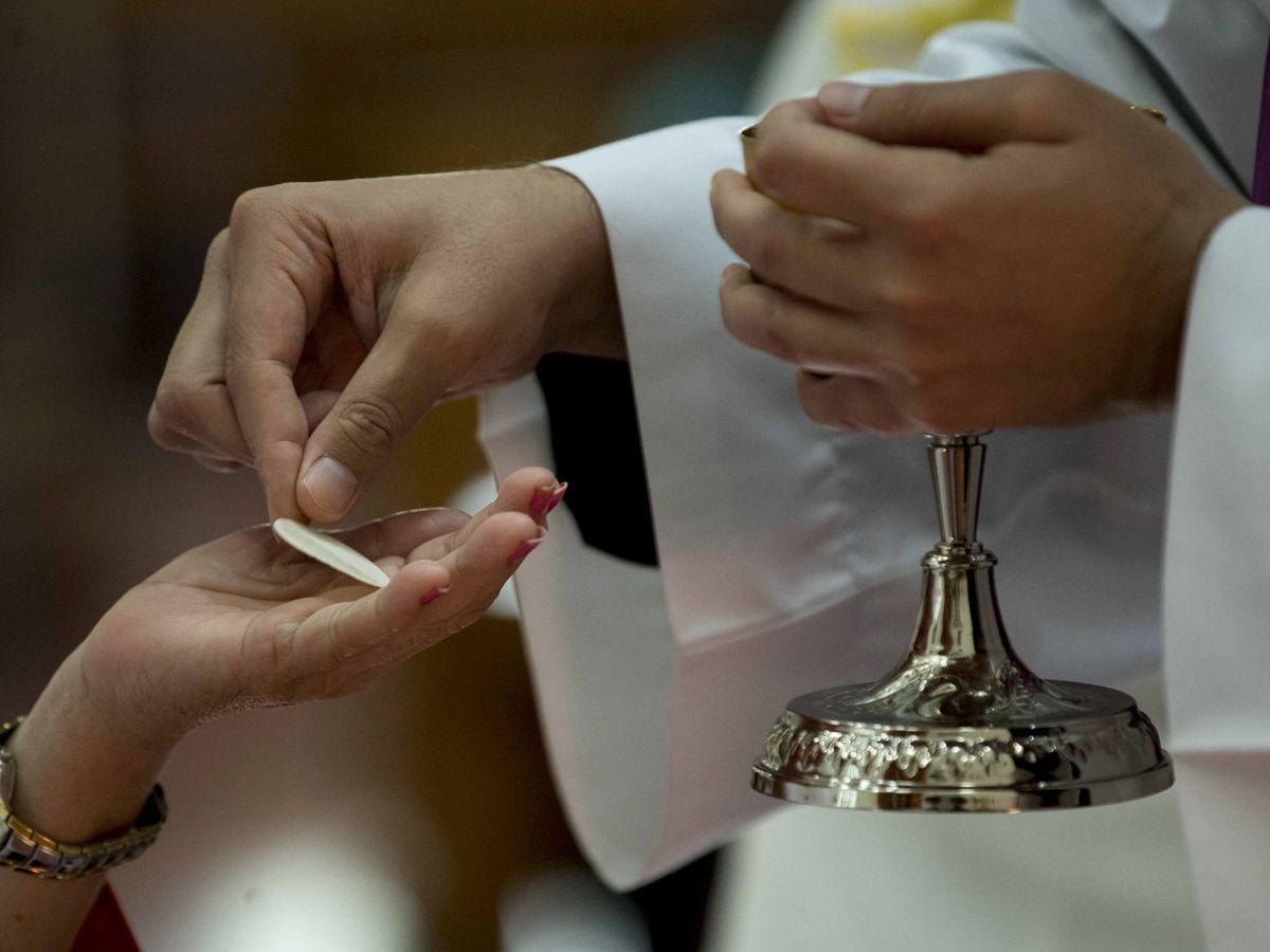 Foto: Un sacerdote entrega una hostia consagrada a un feligrés. (EFE/Jorge Torres)