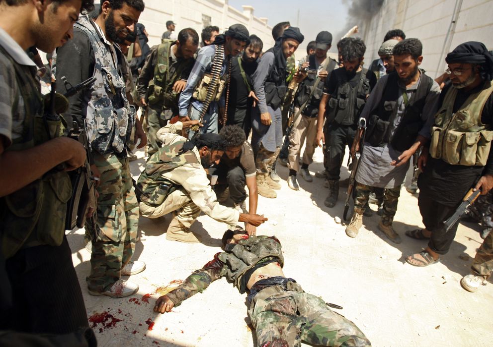 Foto: Combatientes del Ejercito de Liberación Sirio inspeccionan un cadáver durante una ofensiva en Alepo (Reuters).