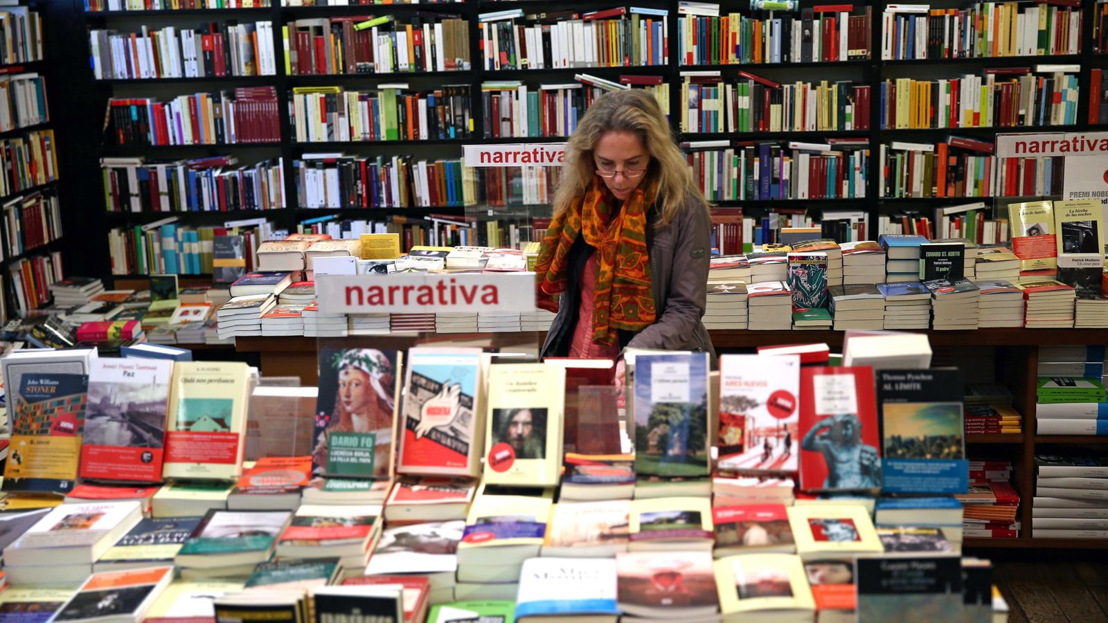 Foto: Una mujer hojea unos libros en una librería de Barcelona (Efe)