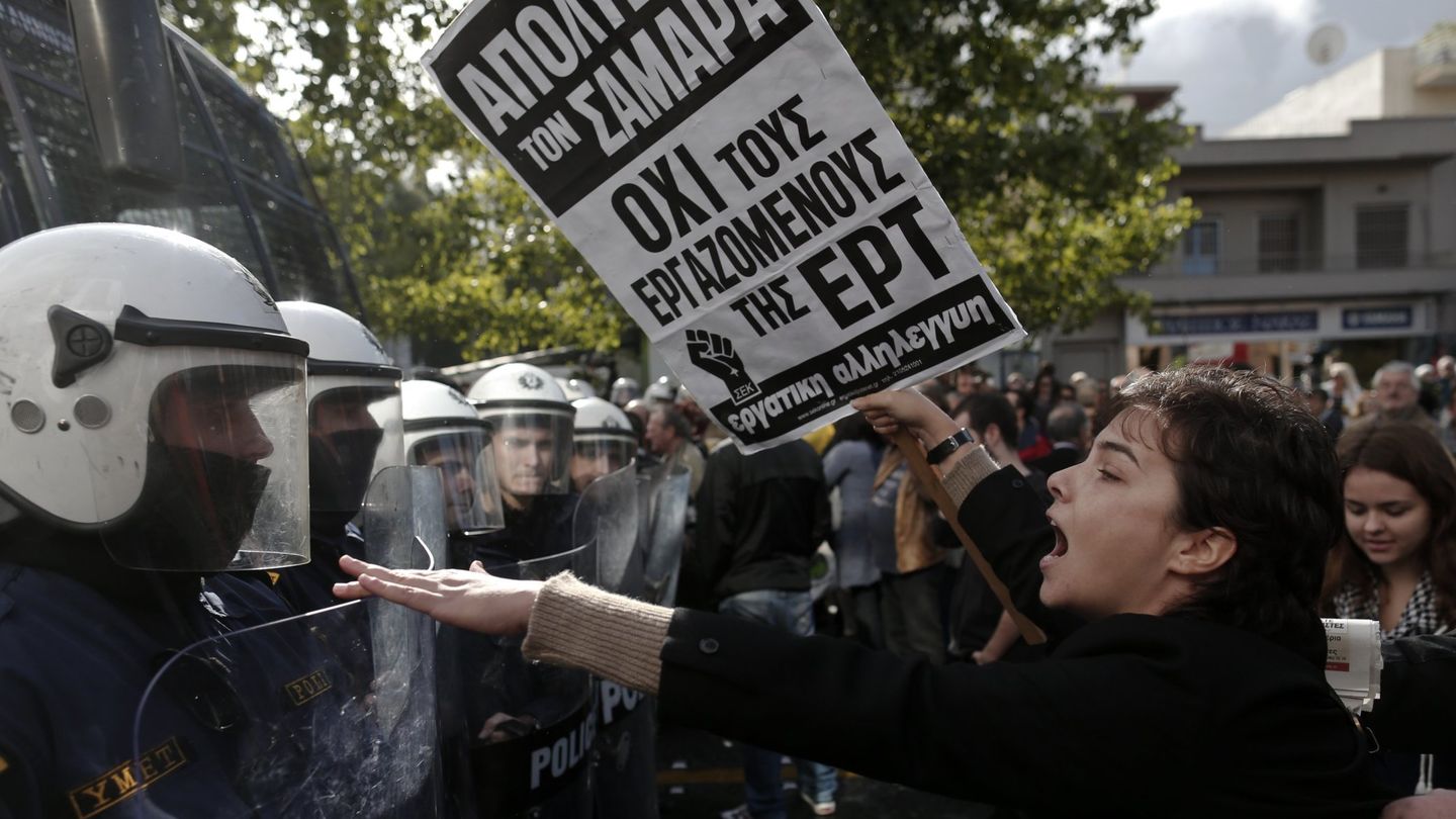 Una manifestante increpa a un policía ante la sede de la  televisión estatal griega, ERT, en Atenas (Reuters).