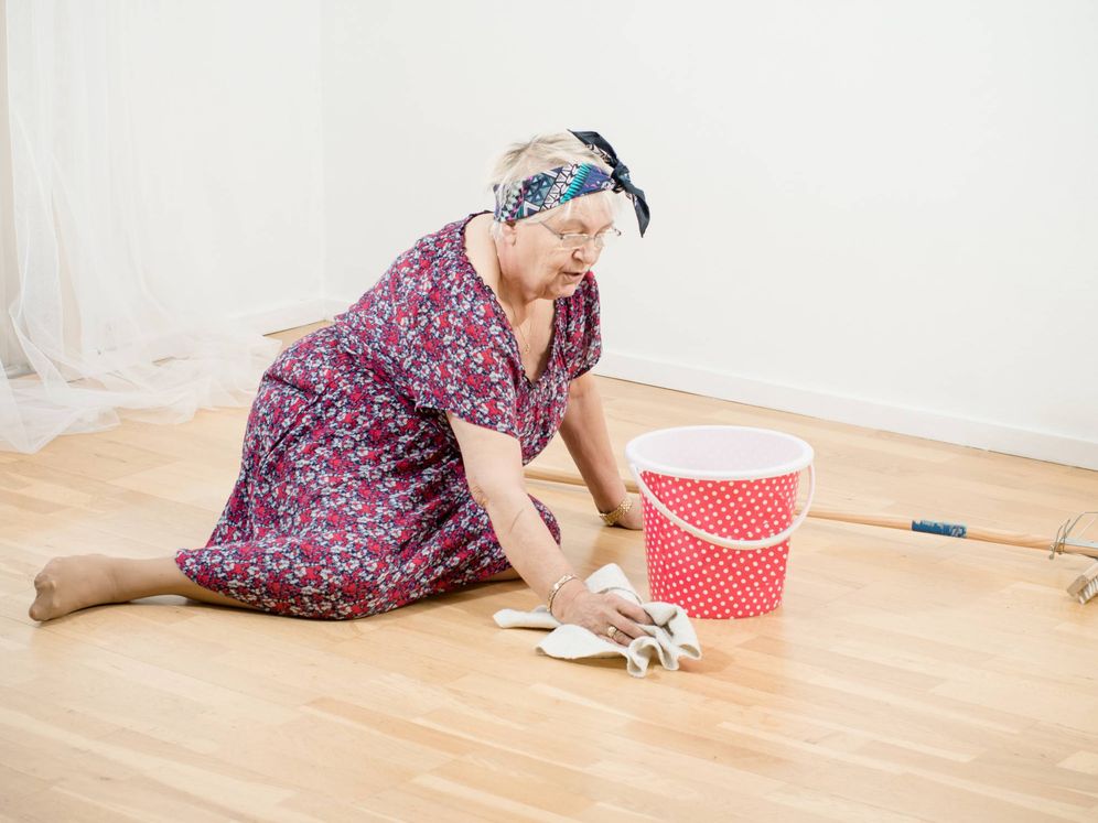 Foto: Ama de casa anciana limpiando el suelo con un trapo. (iStock)