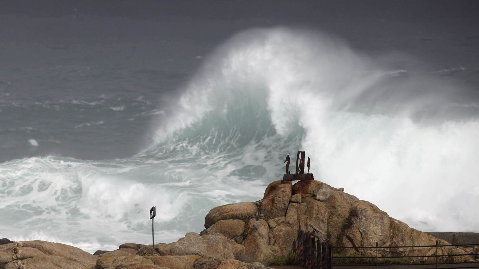 Foto: Una ola rompe contra las rocas del paseo marítimo de La Coruña. (Efe) 