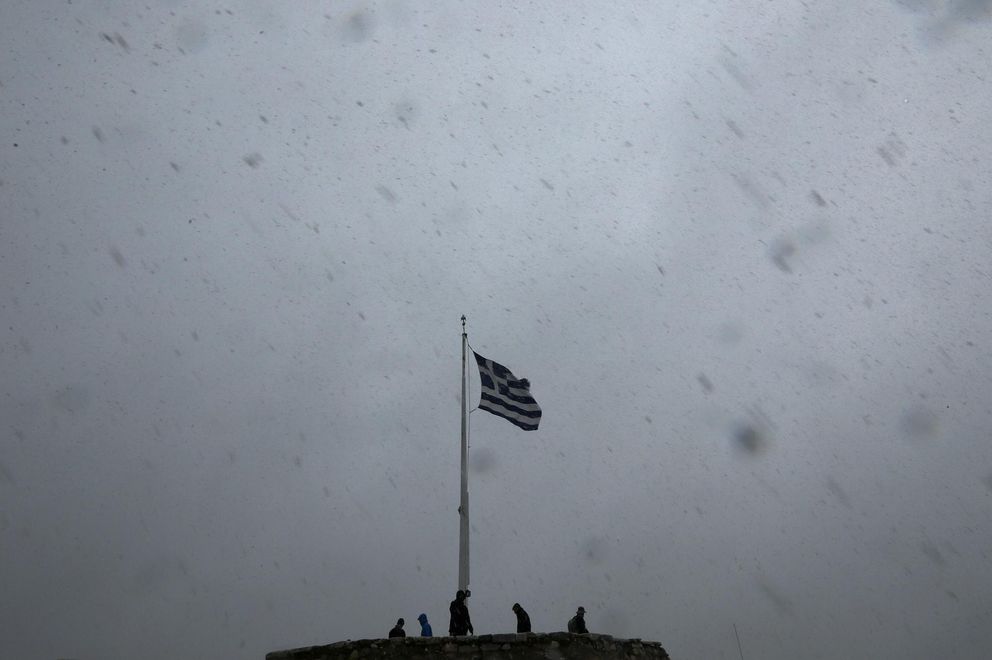 La bandera griega en lo alto de la Acrópolis mientras turistas toman fotografías en medio de una tormenta (Reuters).