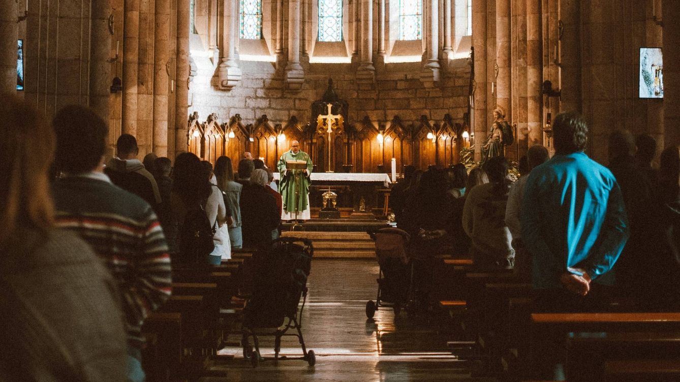 Foto: Varios asistentes rezan durante una misa católica en la Iglesia (Unsplash)
