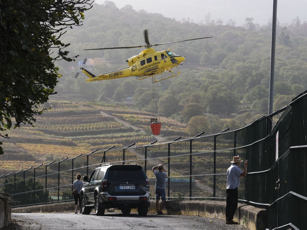 Foto: Varios vecinos de El Sauzal observan un helicóptero que trabaja en las labores de extinción del incendio forestal de Tenerife. (EFE/Alberto Valdés)