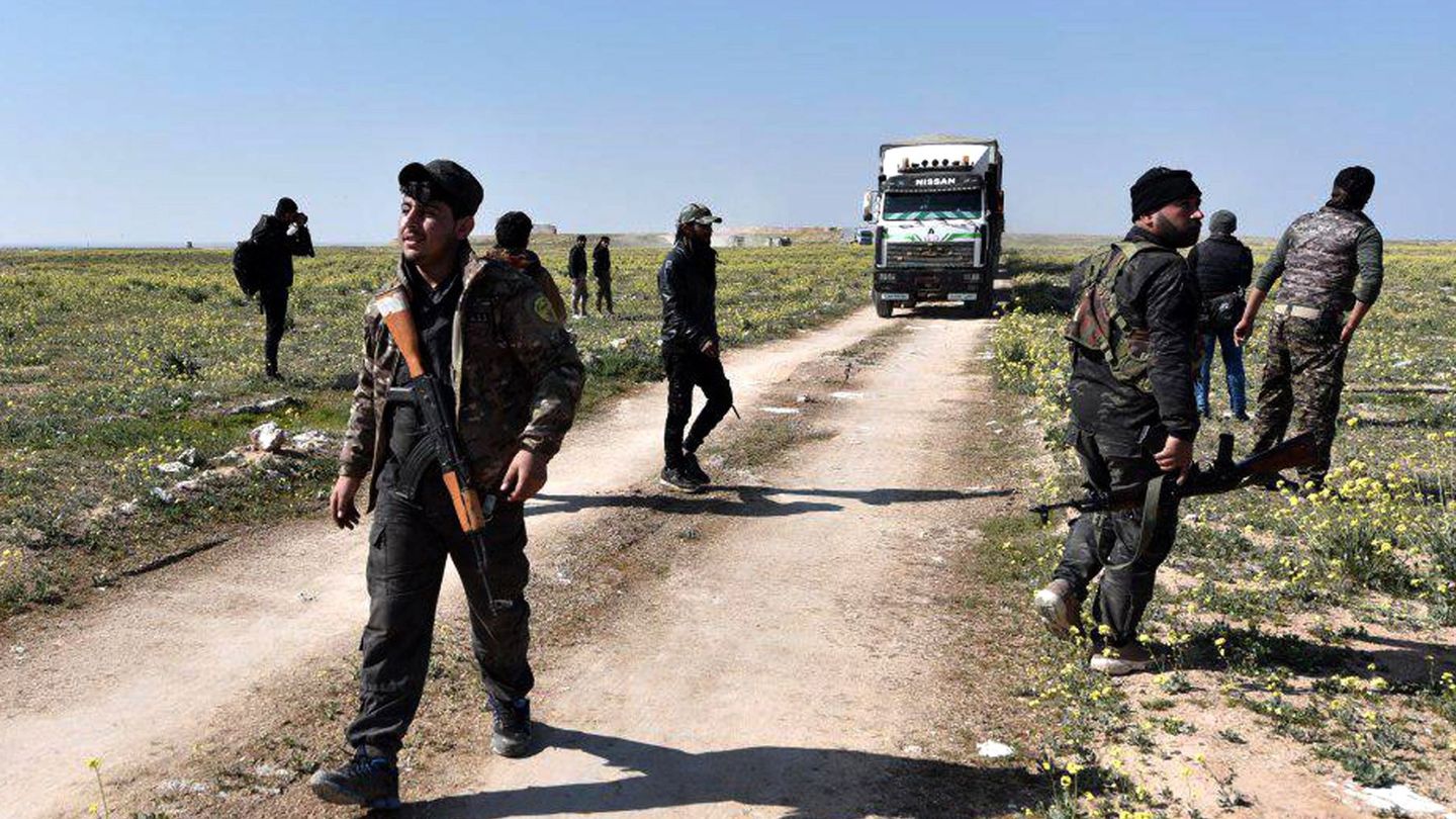 Los combatientes de las Fuerzas Democráticas Sirias (SDF), respaldados por Estados Unidos, observan camiones cargados con personas desplazadas cerca de la ciudad de Baghouz. (EFE)