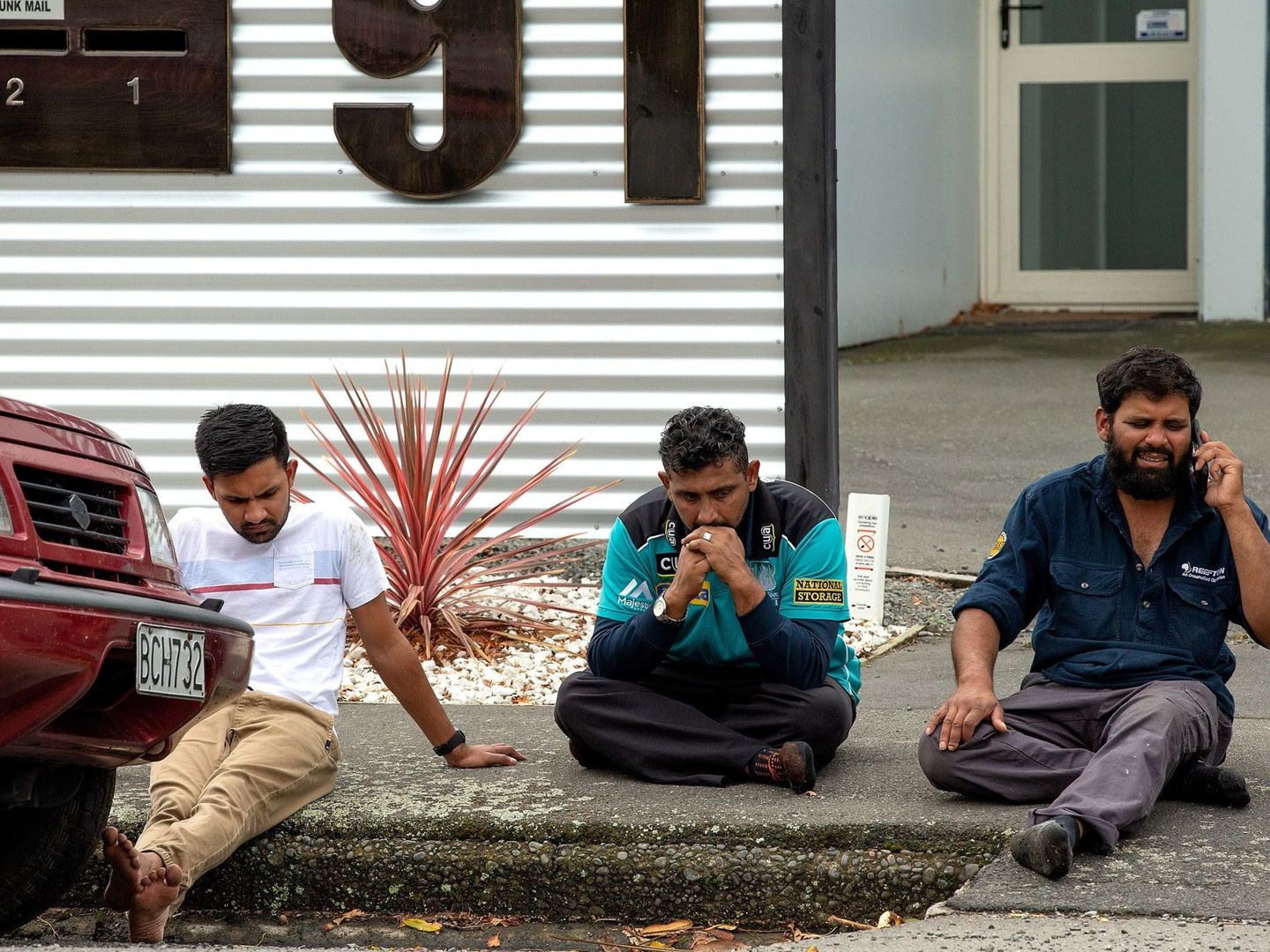 Personas se sientan en una acera después de un atentado que resultó en múltiples muertes en Christchurch. (EFE) 